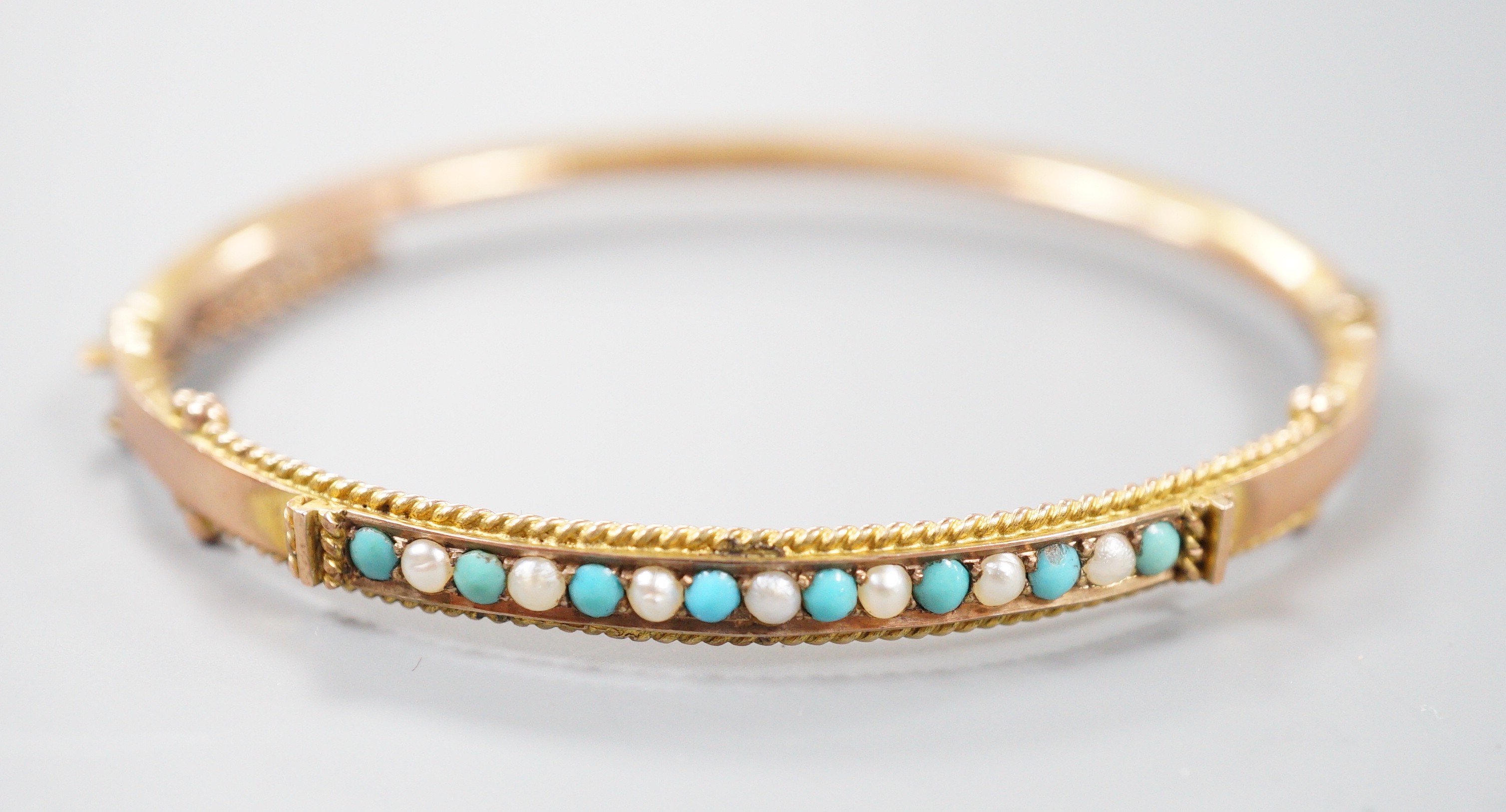 A late Victorian 9ct gold, seed pearl and turquoise set hinged bangle, 58mm, gross weight 6.7 grams.